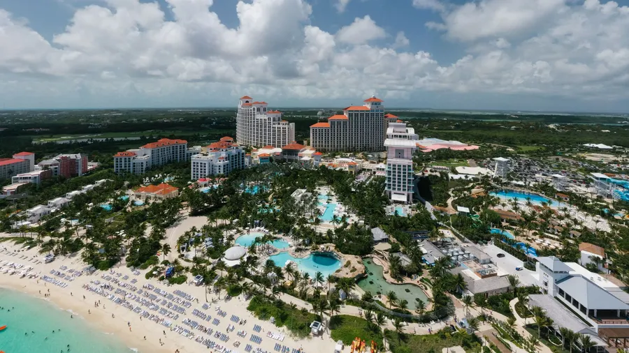 Vista aérea de un resort de lujo junto a la playa en Bahamas, con piscinas y palmeras