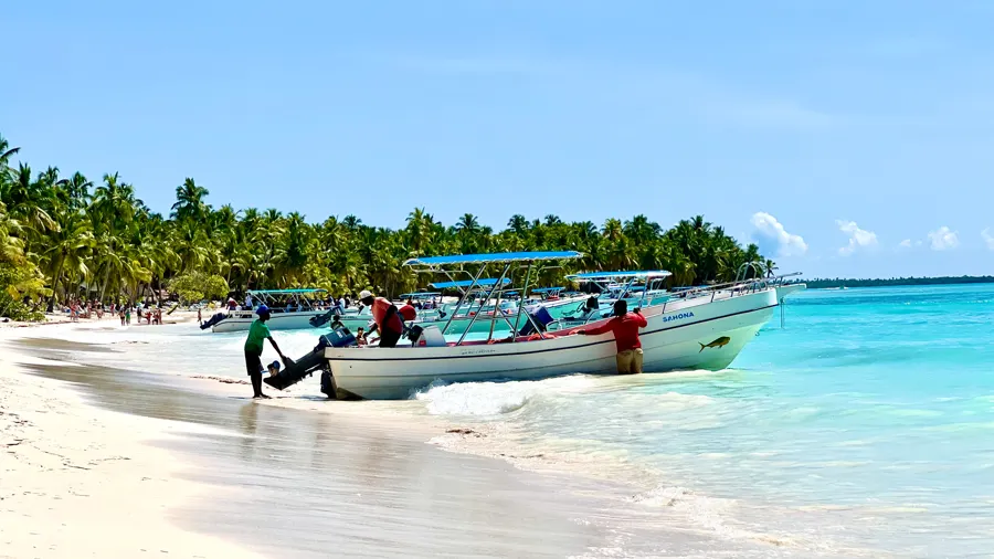 Barcos amarrados en una playa soleada de República Dominicana, con agua turquesa y palmeras