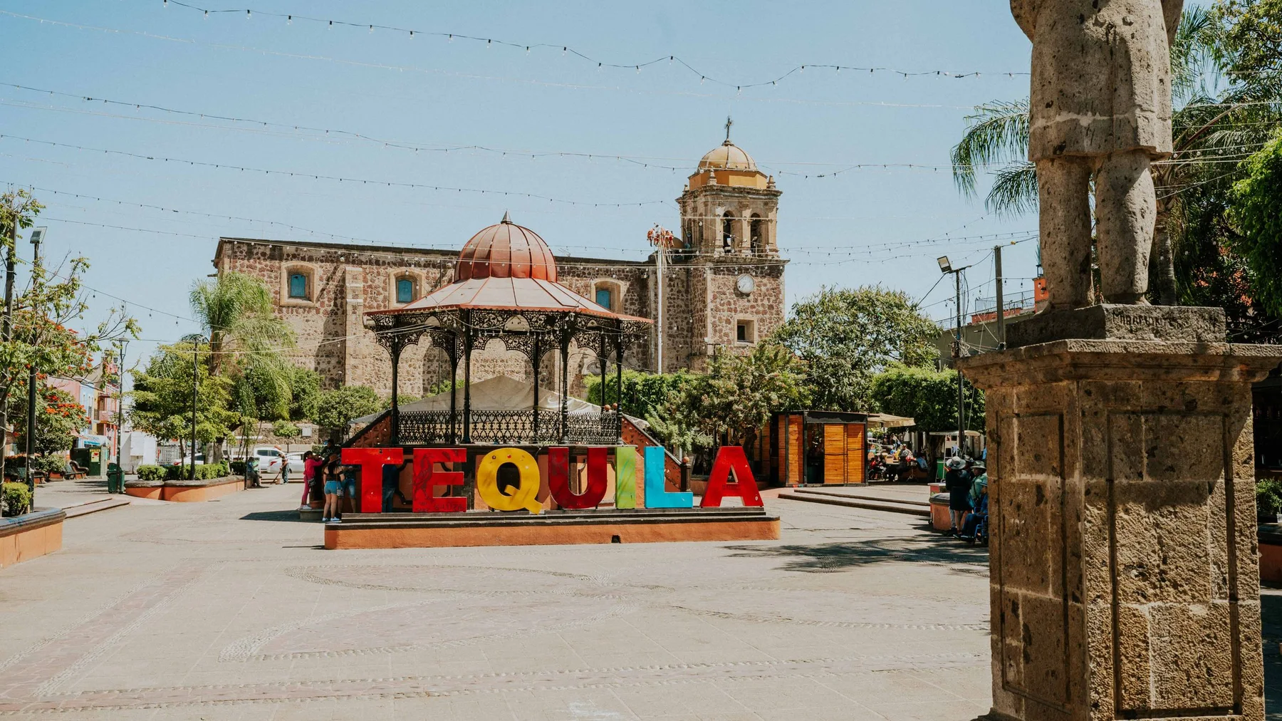 Vibrant Tequila sign in sunny Mexican plaza with historic architecture.