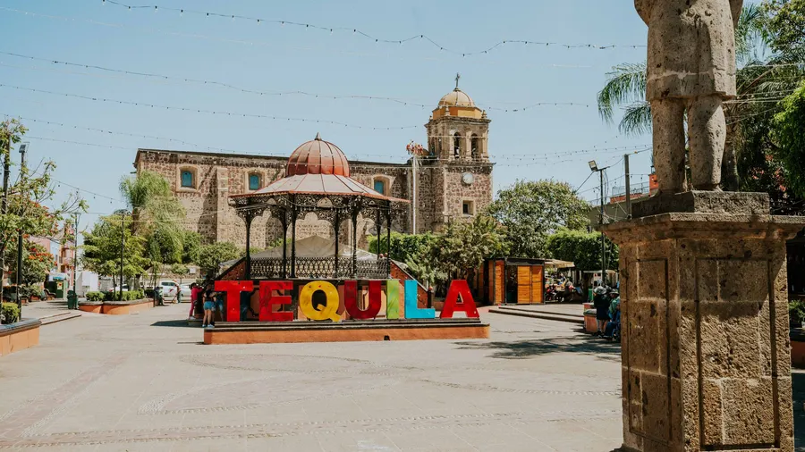 Letrero de Tequila en una plaza soleada de México con arquitectura histórica