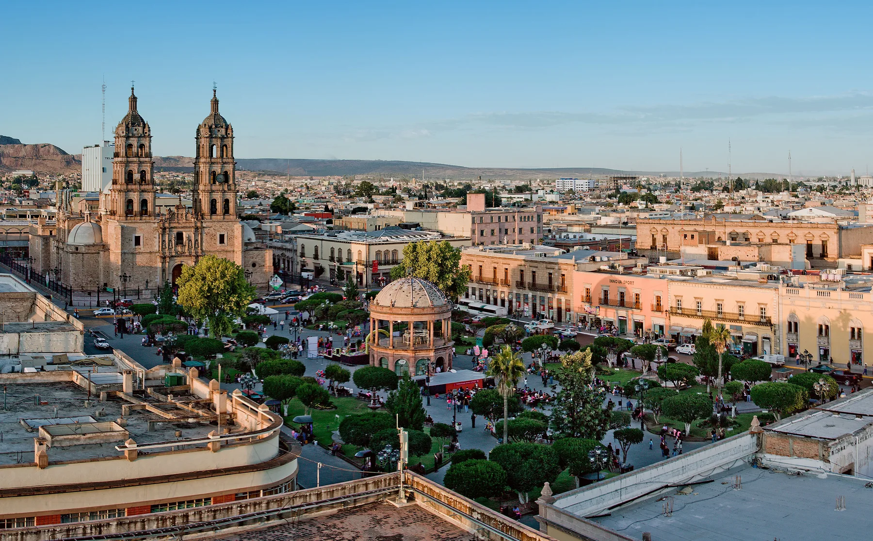 Plaza principal de Durango, México, con árboles, bancas y edificios históricos alrededor