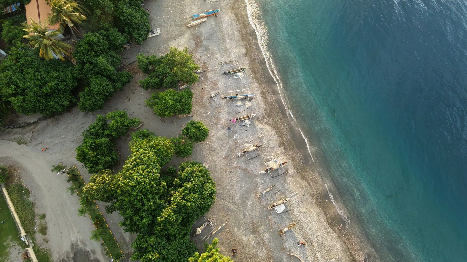 Vista aérea de una playa de Timor Oriental con barcas de pesca y vegetación exuberante