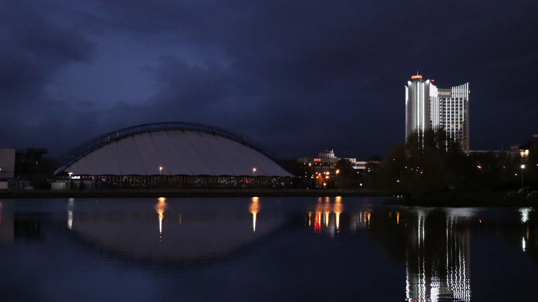 Edificios iluminados reflejados en el río por la noche en Minsk, Bielorrusia