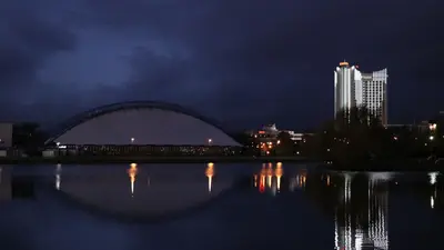 Edificios iluminados reflejados en el río por la noche en Minsk, Bielorrusia