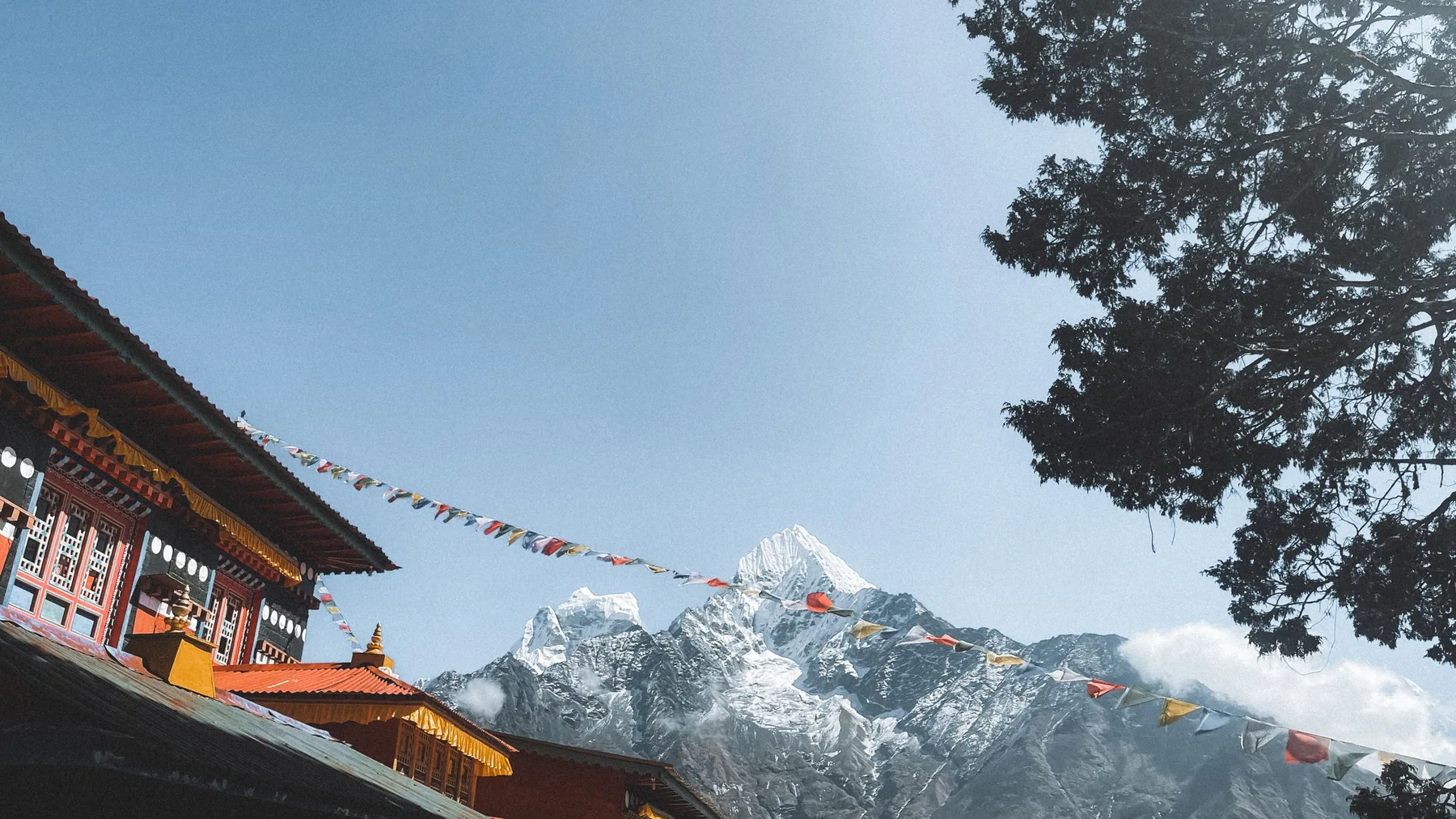 Monasterio budista en Nepal con montañas del Himalaya al fondo y cielo despejado