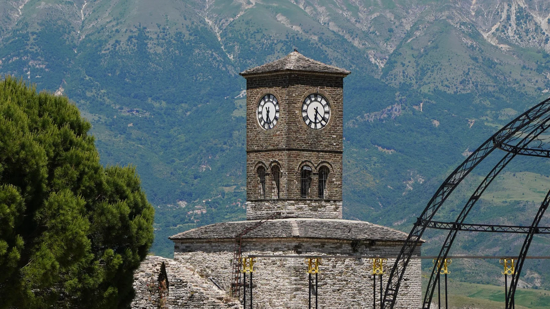 Torre del reloj de piedra con montañas de fondo en Gjirokastër, Albania